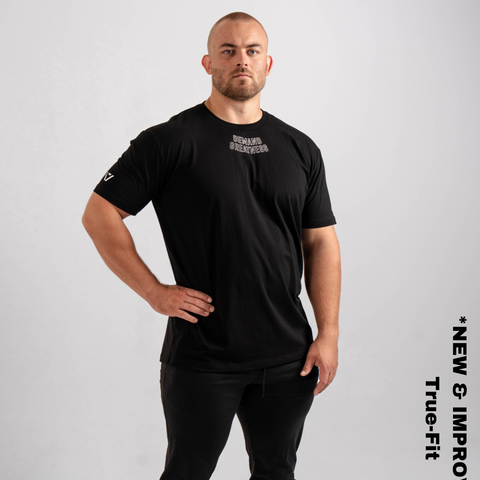 Man wearing A7's IPF Approved domino Meet shirt. 'Demand Greatness’ written on the front of black meet t-shirt in a white double outlined font to have impact on the competition platform. Paired with black powerlifting joggers made from a stretchy material to use in strength sports training. 