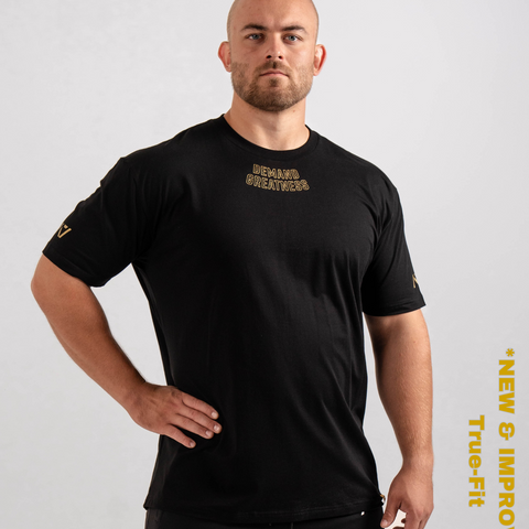 Man wearing A7's IPF Approved Gold Meet shirt. 'Demand Greatness’ written on the front of black meet t-shirt in a gold double outlined font to have impact on the competition platform. Paired with black powerlifting joggers made from a stretchy material to use in strength sports training. 