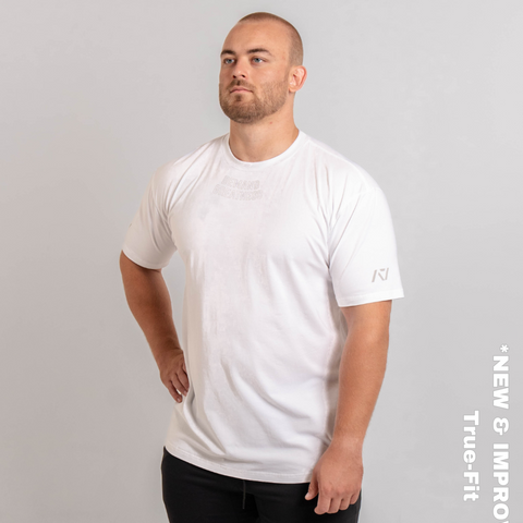 Man wearing A7's IPF Approved Polar white Meet shirt. 'Demand Greatness’ written on the front of white meet t-shirt in a grey double outlined font to have impact on the competition platform. Paired with black powerlifting joggers made from a stretchy material to use in strength sports training. 